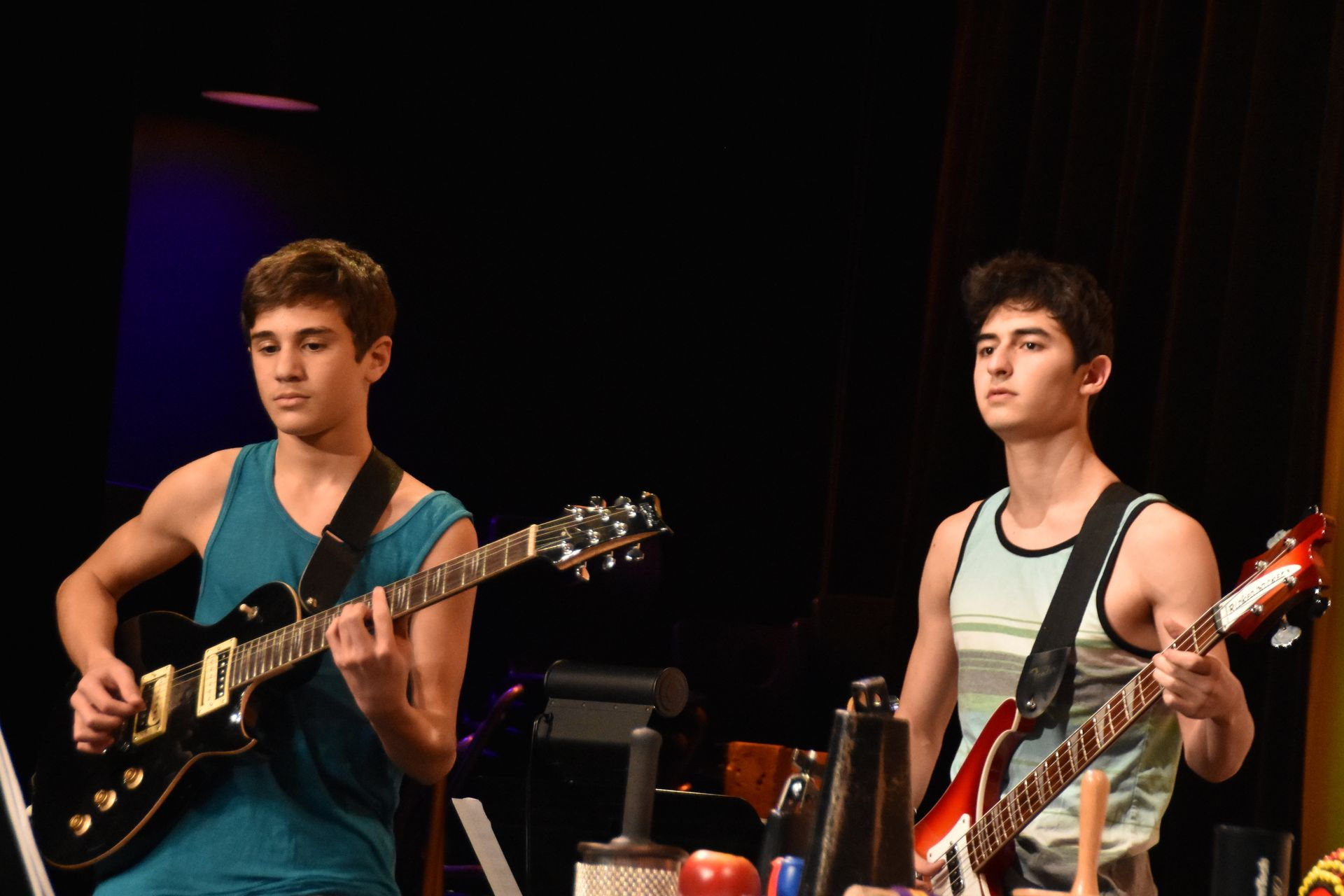An electric gutar player and a bass gutar player wearing tank tops.